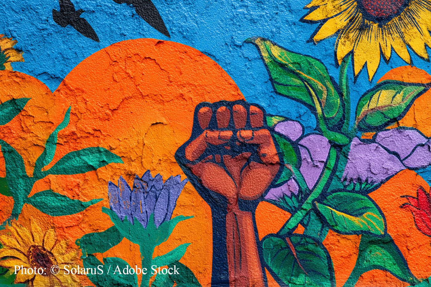 Mural of a raised fist among sunflowers and leaves against an orange sun